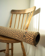 Roll of leopard print paper on a wooden chair against a white wall